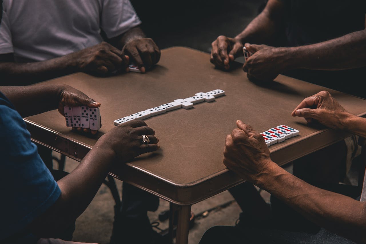 Adults engaging in a game of dominoes around a table, showcasing strategy and fun.